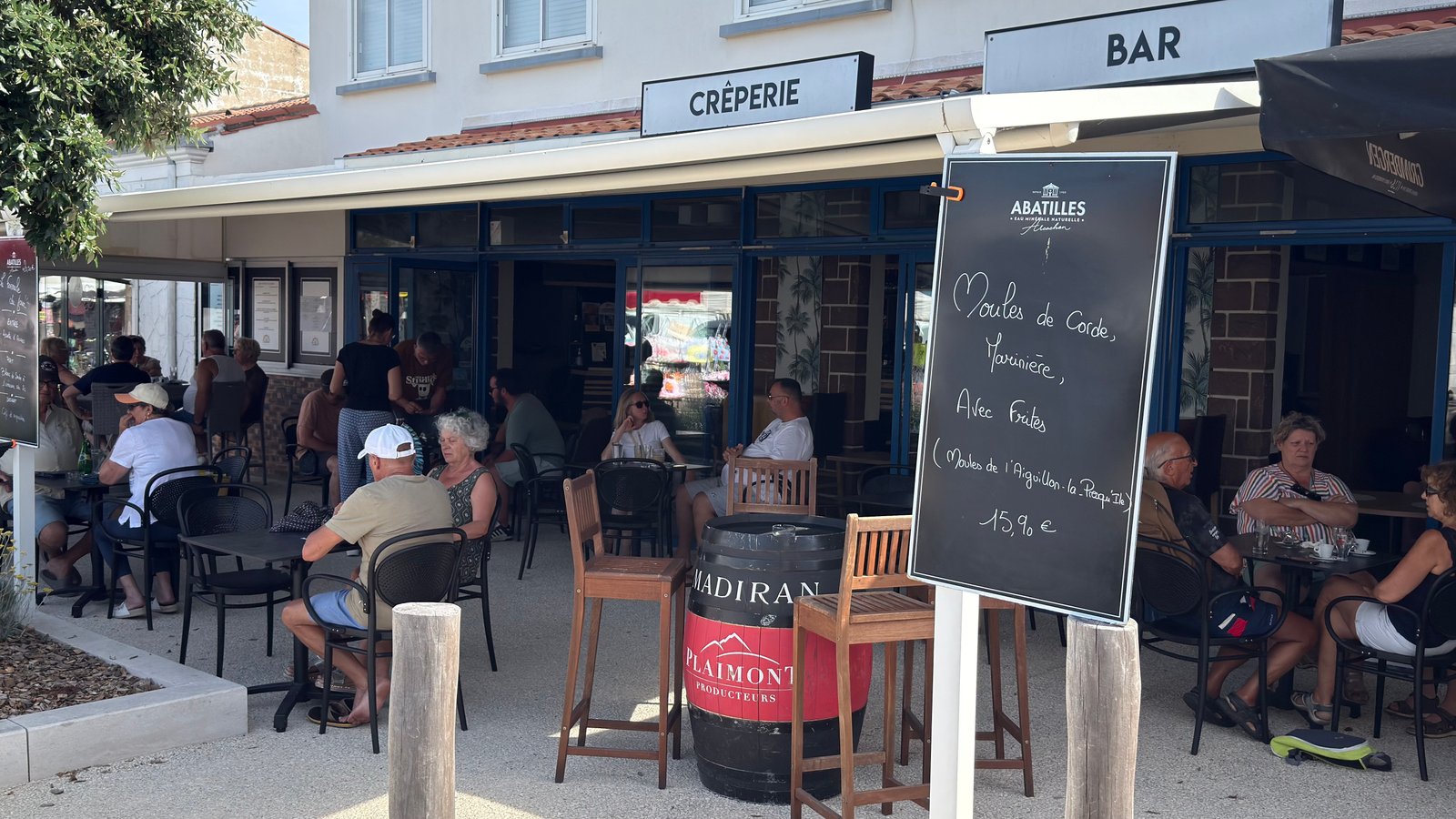 La terrasse de La Goëlette en plein centre du bourg, tables et clients au soleil